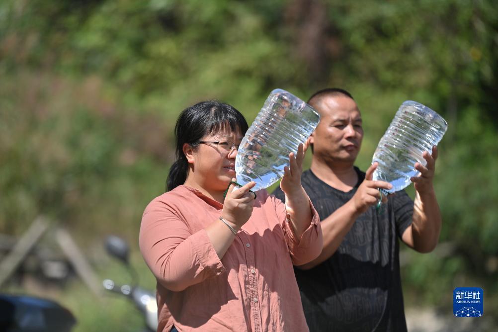 楊寧（左）在查看村民剛剛采集的水樣，為山泉水引水工程做準備（10月8日攝）。新華社記者 黃孝邦 攝